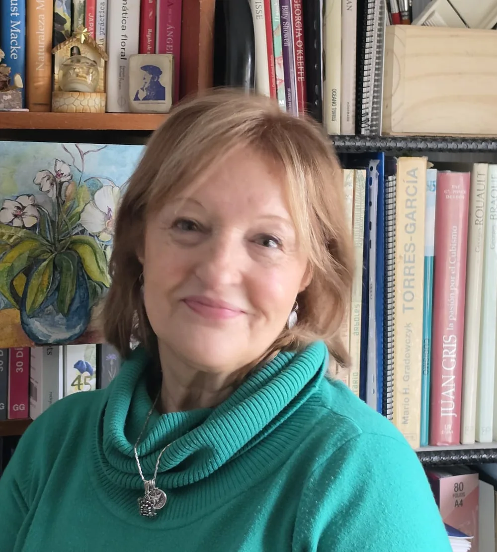 Liliana Donato en su taller, delante de su biblioteca de arte y de una de sus pinturas.